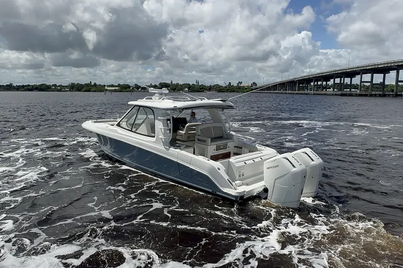  Yacht Photos Pics 2023 Boston Whaler 380 Realm cruising on a river under cloudy skies.