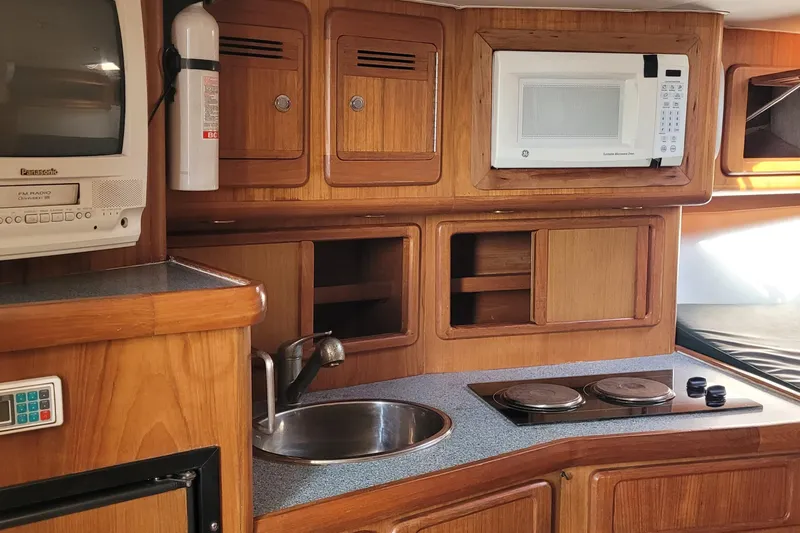 Wave Dancer Yacht Photos Pics 2002 SeaTek 36 Express yacht kitchen with microwave, stove, and wooden cabinetry.