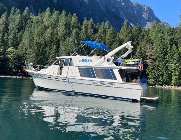  Yacht Photos Pics 1988 Bayliner 4588 yacht on serene lake, surrounded by lush forest and mountains.