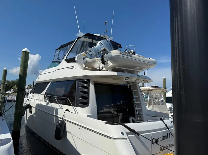 Captain & The Kids Yacht Photos Pics 1998 Carver 530 VOYAGER yacht docked, featuring upper deck with dinghy, clear sky background.