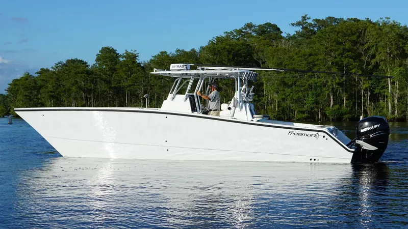  Yacht Photos Pics 2023 Freeman 34VH boat on a calm lake with forested background.