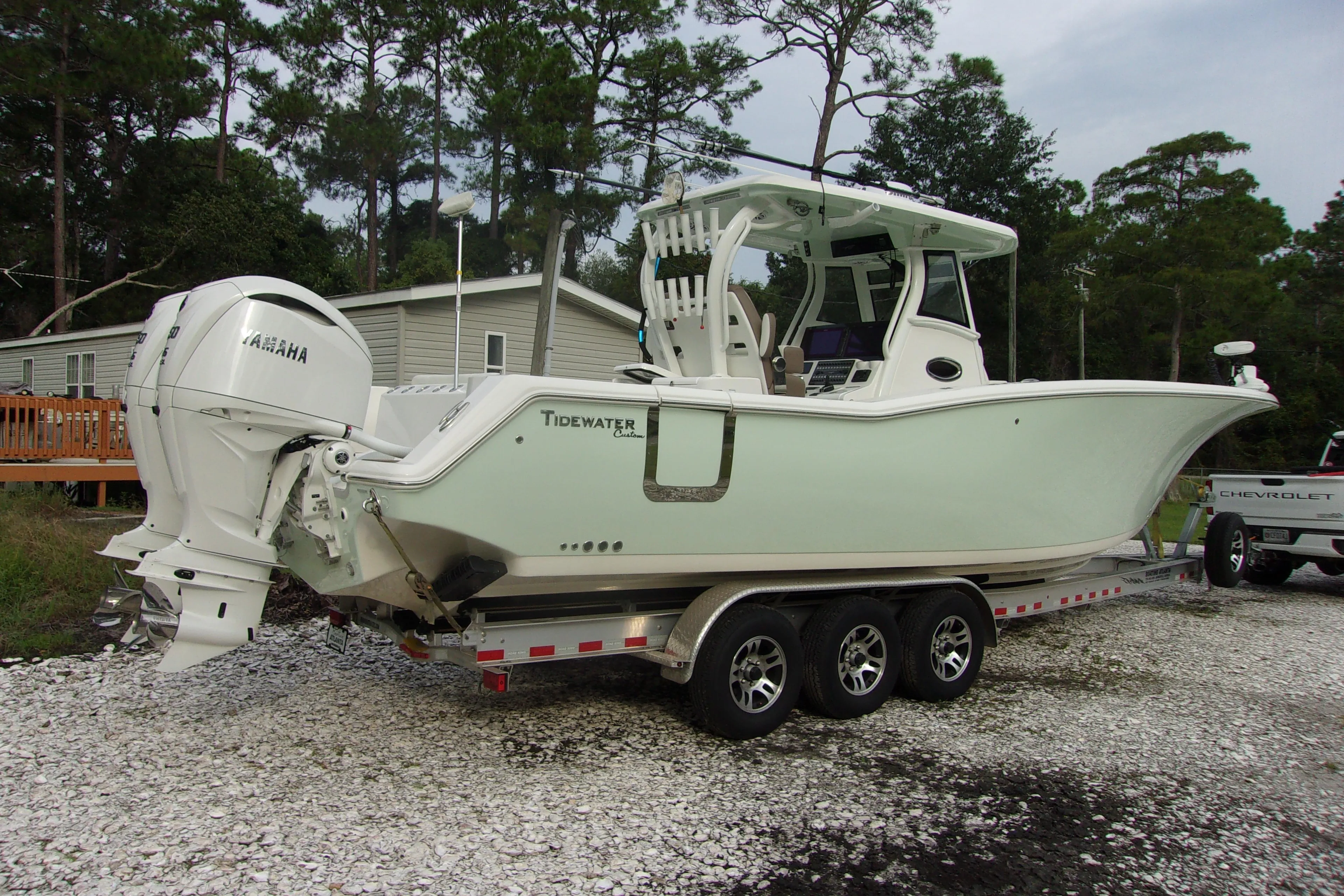 2025 Tidewater 320 CC Adventure boat on trailer, parked outdoors near trees.