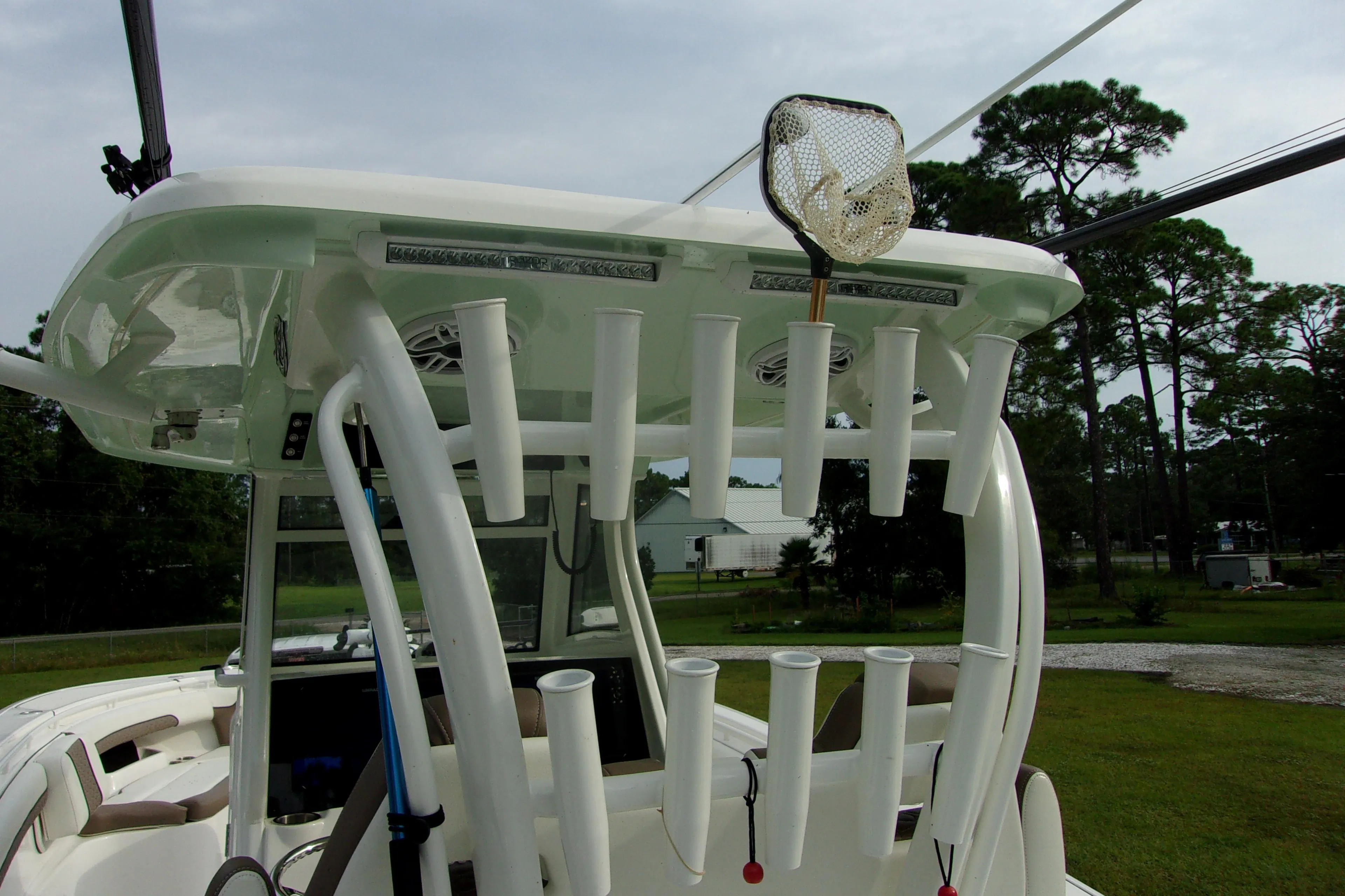 2025 Tidewater 320 CC Adventure boat with rod holders and fishing net, parked outdoors.