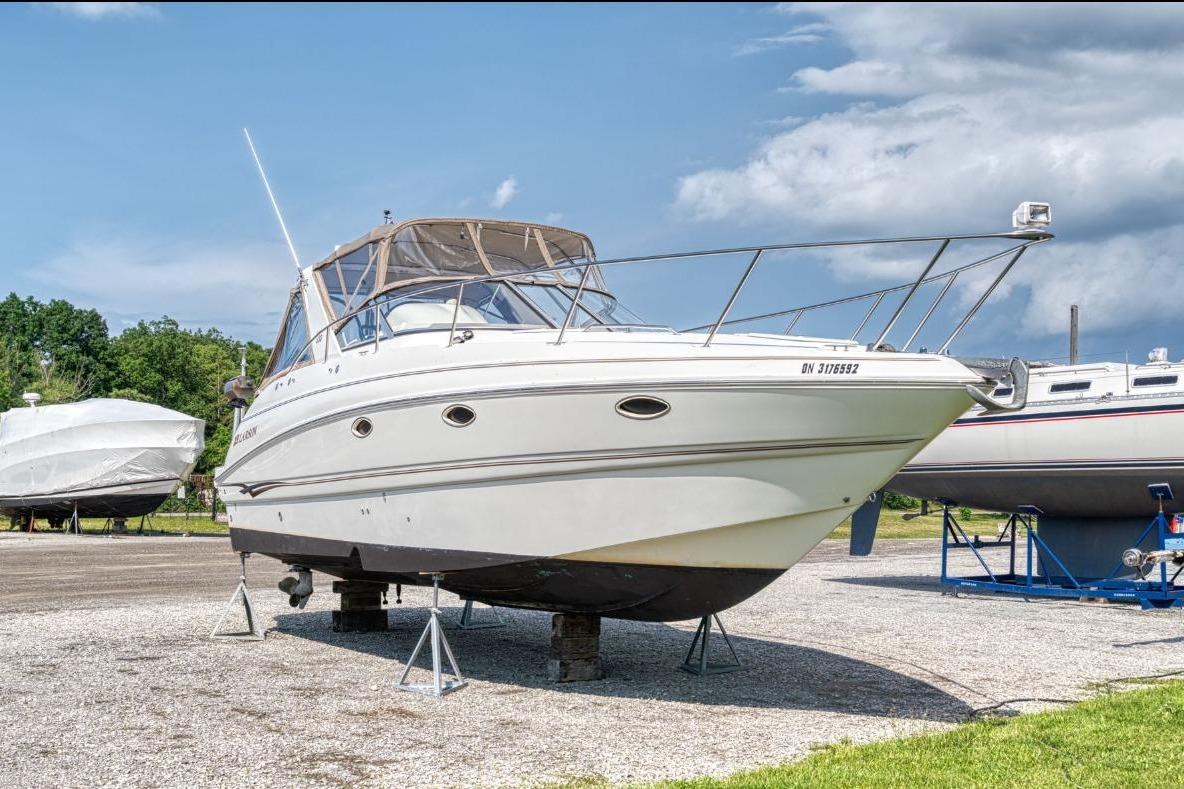 2002 Larson Cabrio 330 boat on stands, outdoor storage, clear sky background.