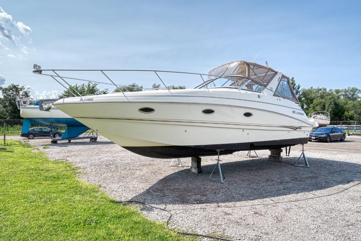 2002 Larson Cabrio 330 boat on stands in a sunny outdoor setting.