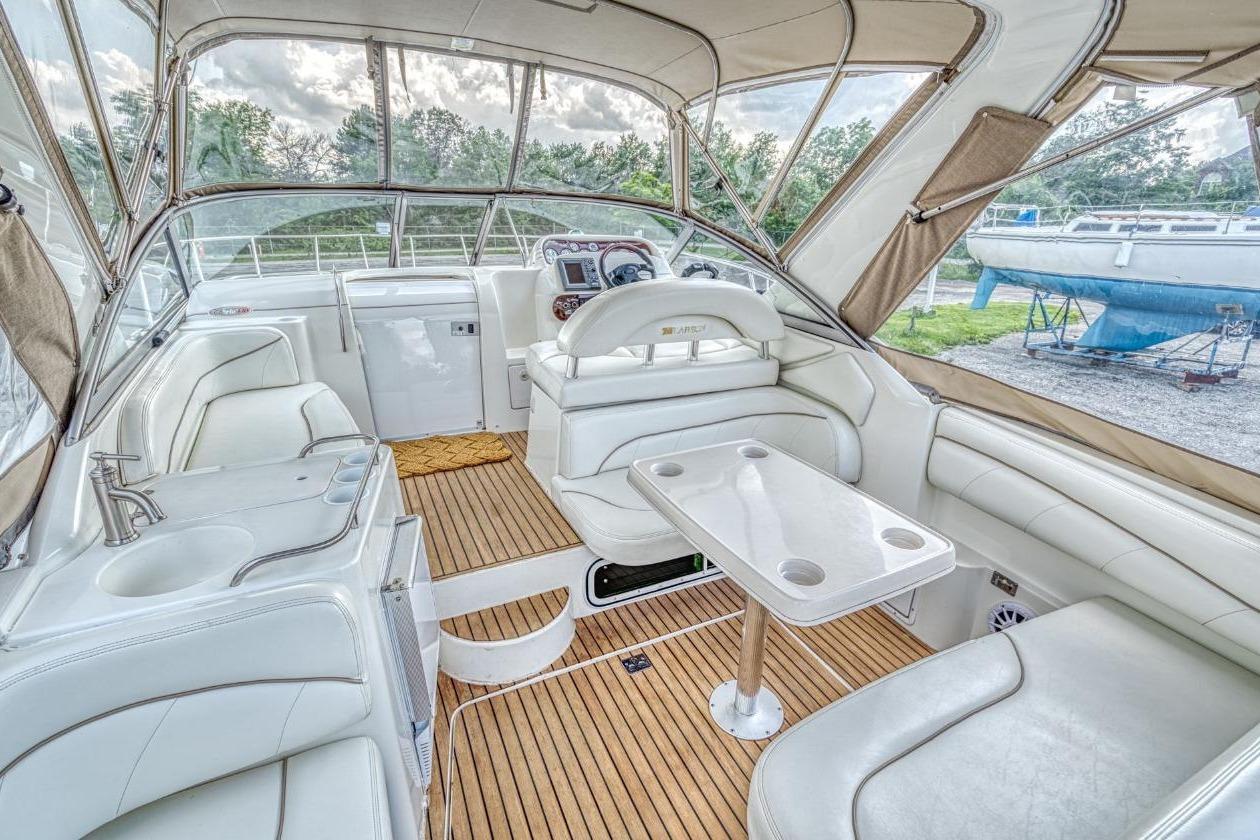 Luxurious interior of a 2002 Larson Cabrio 330 boat with white seating and wood flooring.