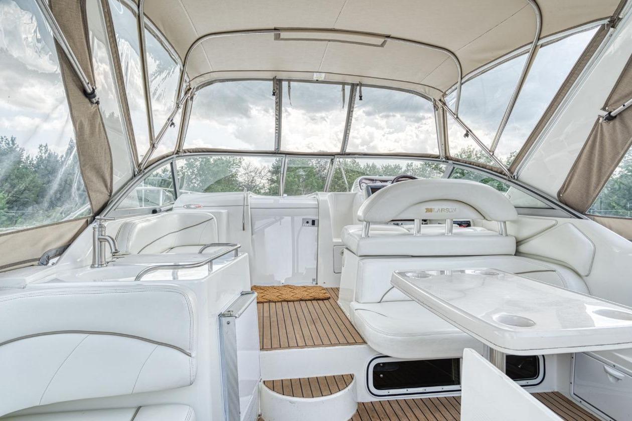 Interior of 2002 Larson Cabrio 330 boat with white seating and wooden flooring.