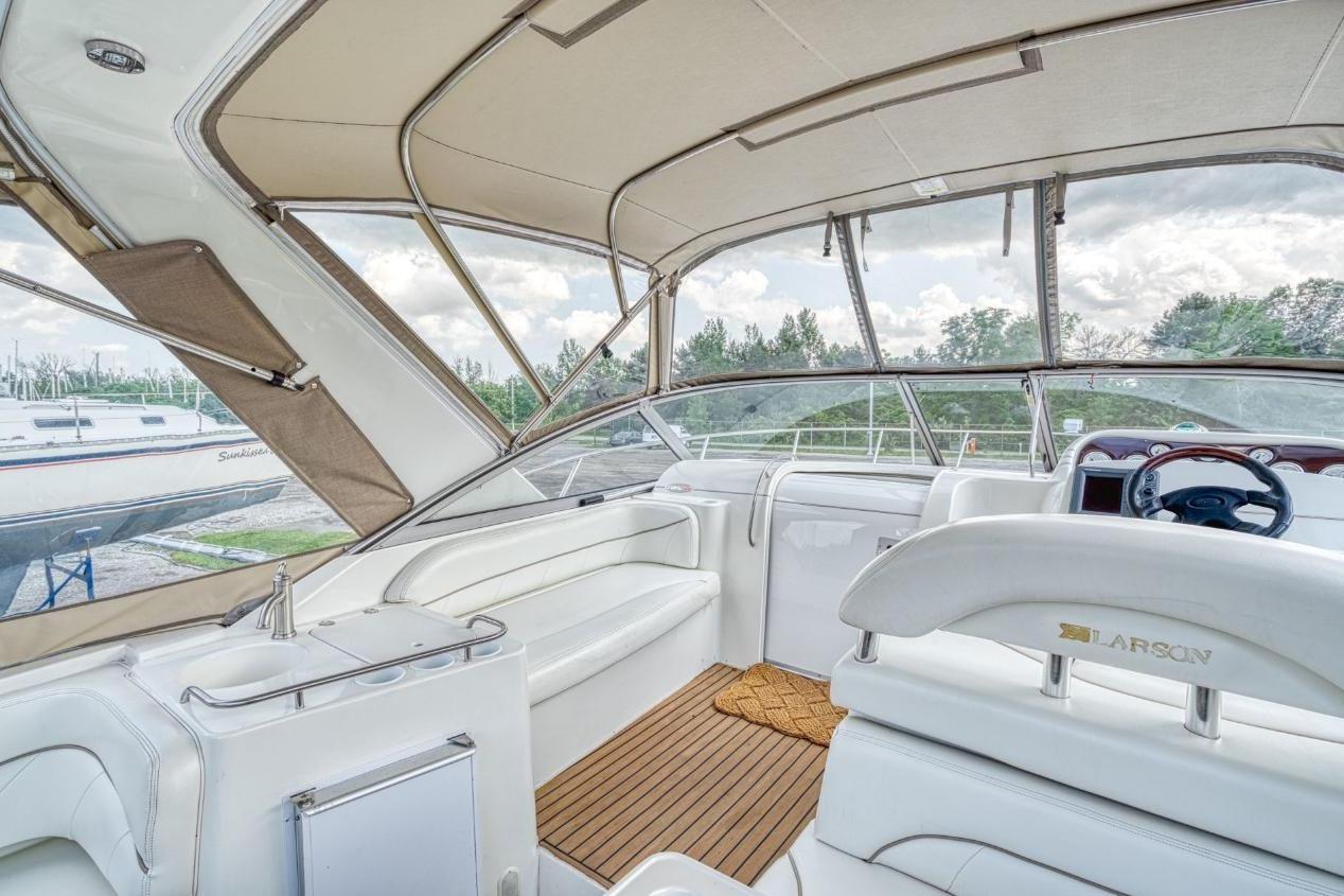 Interior of 2002 Larson Cabrio 330 boat with white seating and wood flooring.