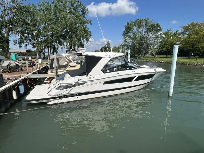  Yacht Photos Pics 2017 Four Winns H350 boat docked on a sunny day, surrounded by trees and calm water.