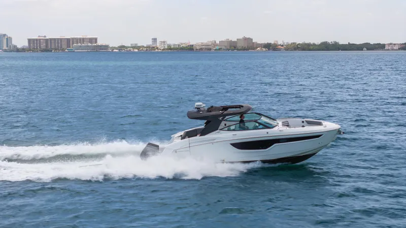  Yacht Photos Pics 2020 Cruisers Yachts 38 GLS OB speeding on open water, cityscape in background.