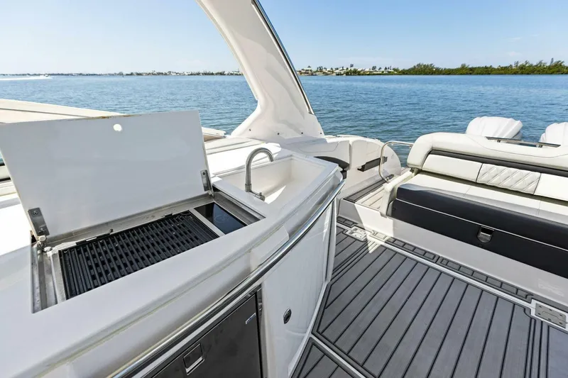  Yacht Photos Pics 2022 Regal 33 OBX boat interior with grill and seating, overlooking serene water.