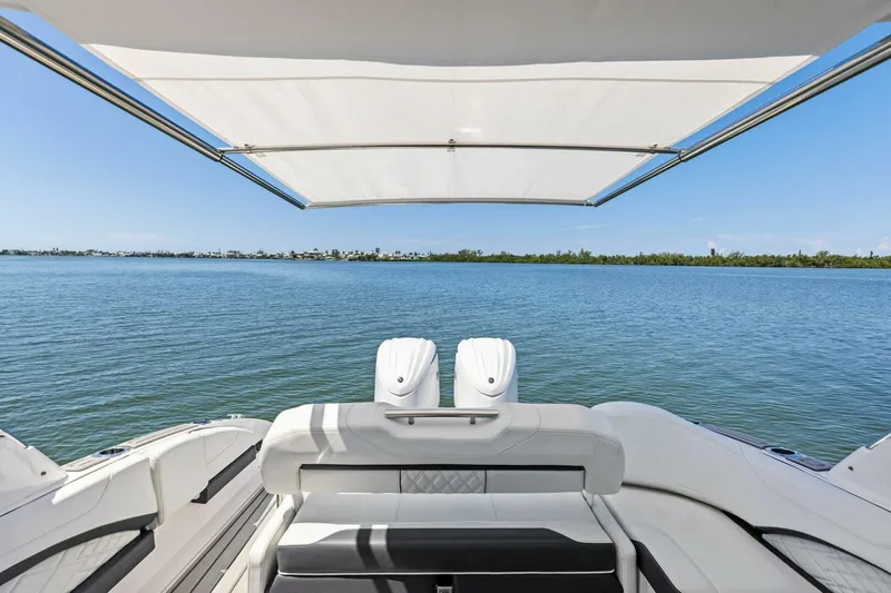  Yacht Photos Pics 2022 Regal 33 OBX boat with canopy, overlooking serene blue waters and distant shoreline.