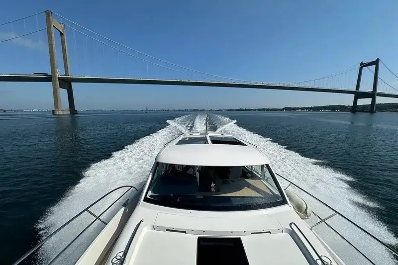 Bertie Yacht Photos Pics Nimbus 405 Coupé 2024 cruising under a large bridge on a sunny day.