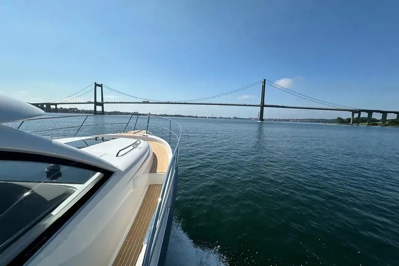 Bertie Yacht Photos Pics 2024 Nimbus 405 Coupé cruising under a scenic bridge on a sunny day.