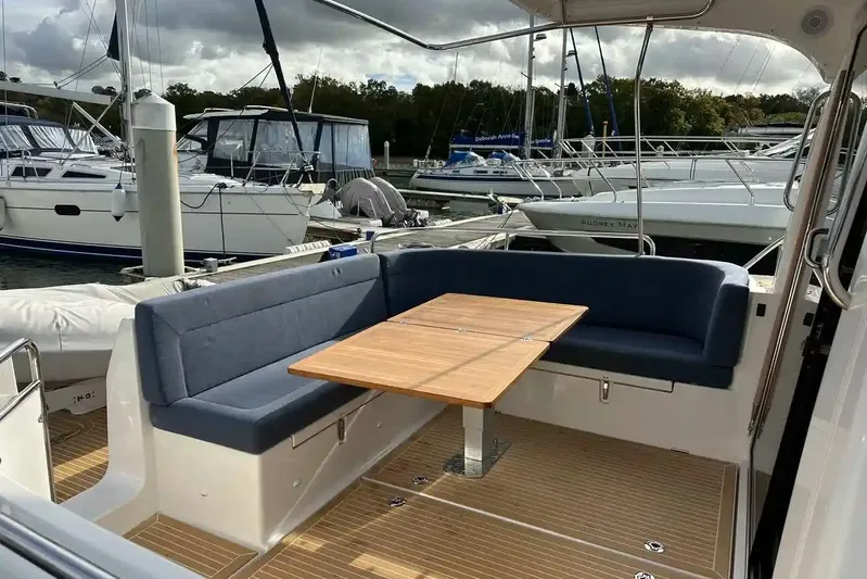 Bertie Yacht Photos Pics 2024 Nimbus 405 Coupé yacht with elegant outdoor seating and wooden table in marina setting.