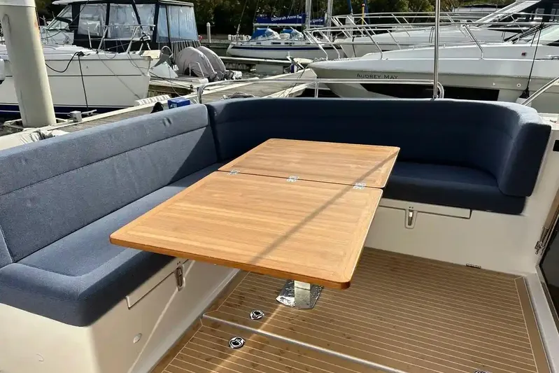Bertie Yacht Photos Pics 2024 Nimbus 405 Coupé yacht with elegant seating and wooden table in marina setting.