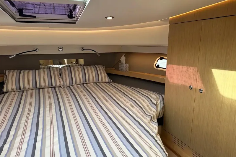 Bertie Yacht Photos Pics Luxurious bedroom interior of 2024 Nimbus 405 Coupé yacht with striped bedding.