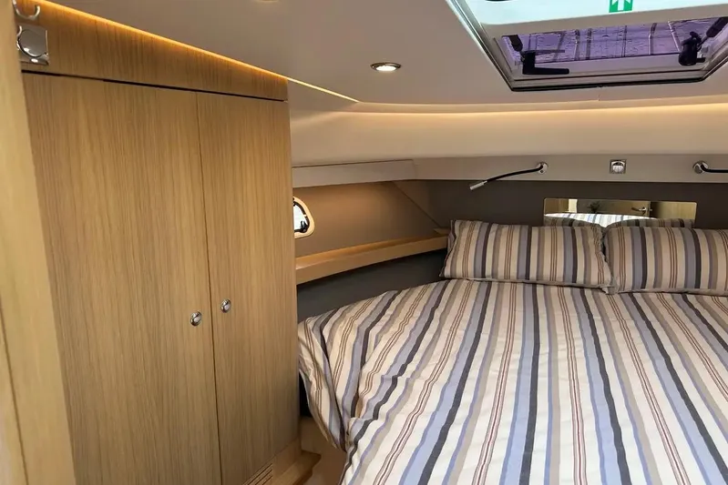 Bertie Yacht Photos Pics Luxurious cabin interior of 2024 Nimbus 405 Coupé with striped bedding and wooden cabinetry.