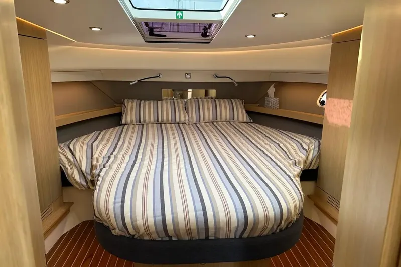 Bertie Yacht Photos Pics Luxurious bedroom interior of 2024 Nimbus 405 Coupé yacht with striped bedding.