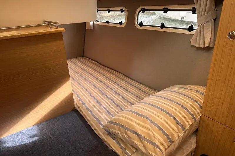 Bertie Yacht Photos Pics Cozy cabin interior of 2024 Nimbus 405 Coupé with striped bedding and porthole windows.