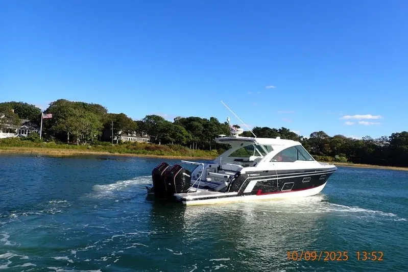  Yacht Photos Pics 2022 Formula 380 Super Sport Crossover OB cruising on a sunny day near a wooded shoreline.