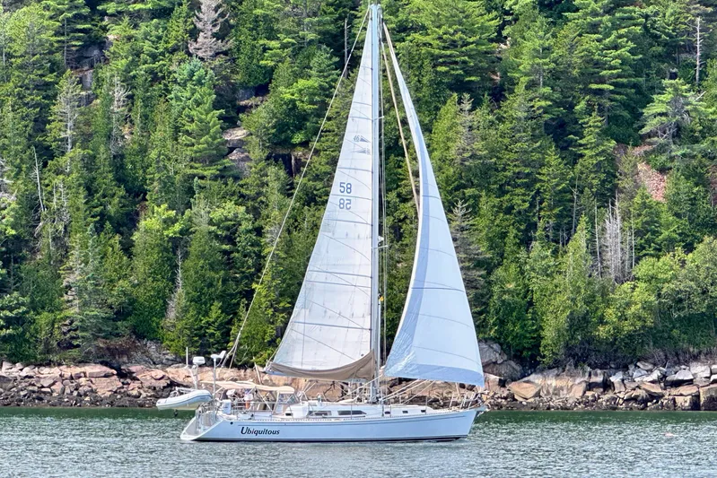 Ubiquitous Yacht Photos Pics Sailboat "Ubiquitous" on water, Outbound 46 model, 2015, with lush forest backdrop.