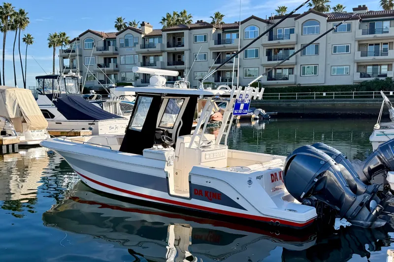 Da Kine Yacht Photos Pics 2022 Robalo R272 Center Console boat docked in marina, with modern buildings in background.