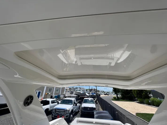  Yacht Photos Pics 2022 Sea Ray SLX 310 boat interior with sunroof, parked near trucks and houses.