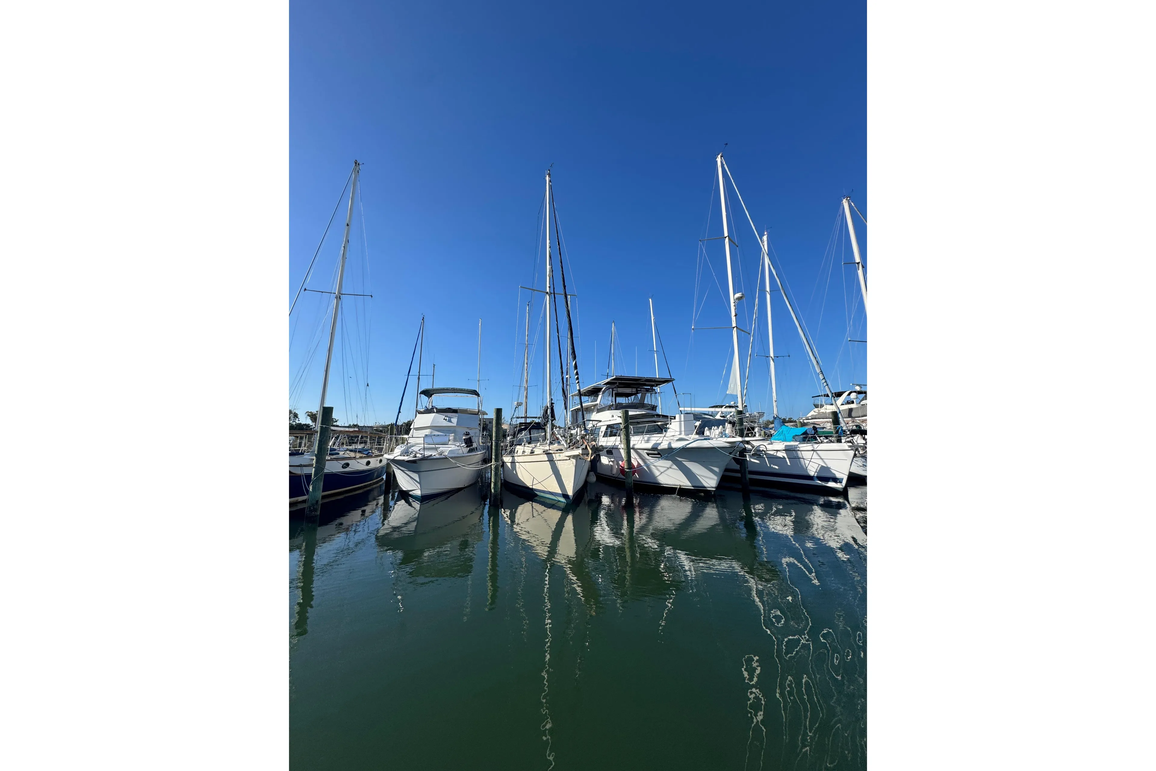 Sailboats docked at marina under clear blue sky, featuring 1991 Island Packet Yachts 38.