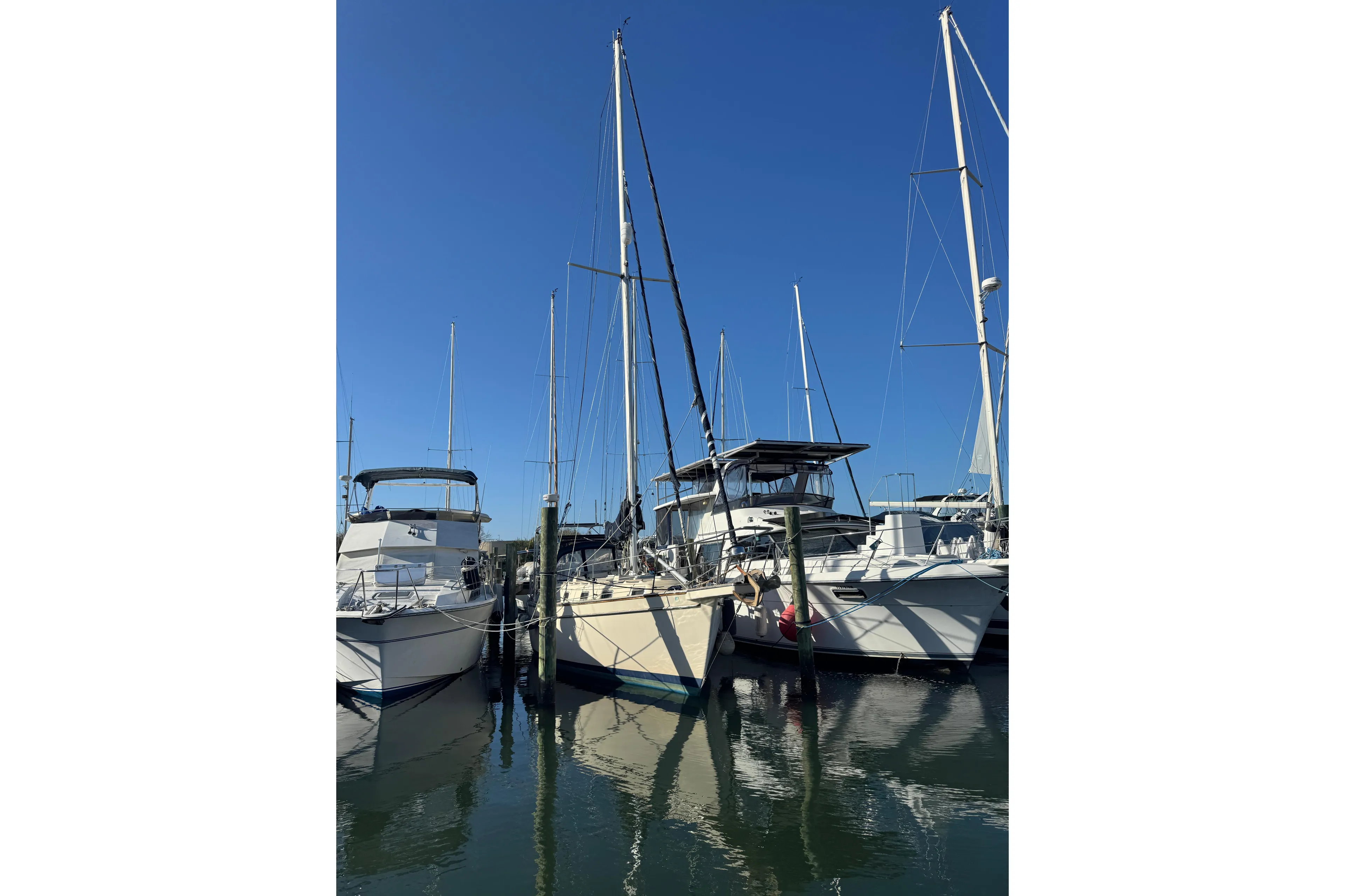 Sailboats docked at marina, featuring a 1991 Island Packet Yachts 38 under clear blue sky.