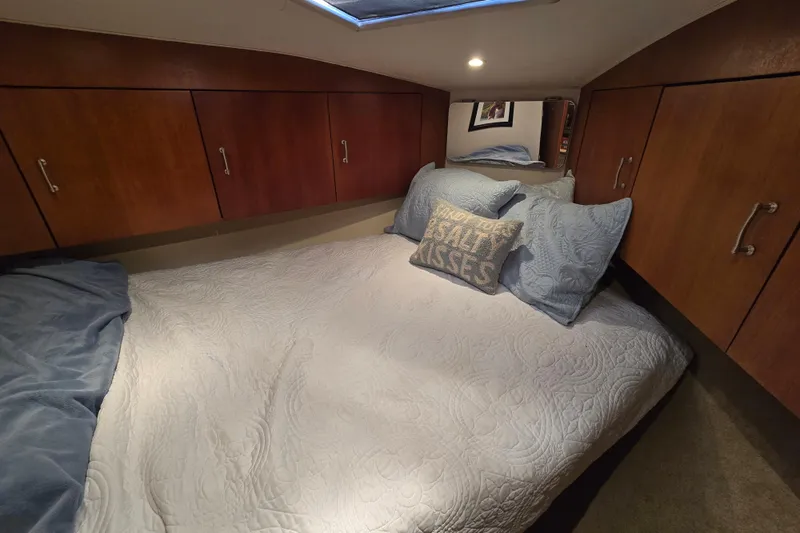  Yacht Photos Pics Cozy cabin bedroom in 1999 Ocean Yachts 40 Open, featuring wood cabinets and nautical decor.