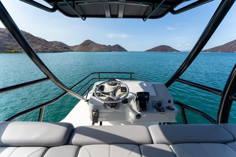 Fast Kash Yacht Photos Pics 2023 Boston Whaler 420 Outrage helm view, overlooking serene blue waters and distant hills.