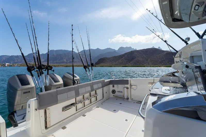 Fast Kash Yacht Photos Pics 2023 Boston Whaler 420 Outrage boat with fishing rods, scenic mountain backdrop.