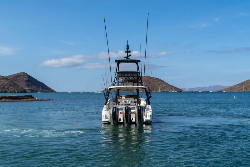 Fast Kash Yacht Photos Pics 2023 Boston Whaler 420 Outrage boat on water, surrounded by scenic hills.
