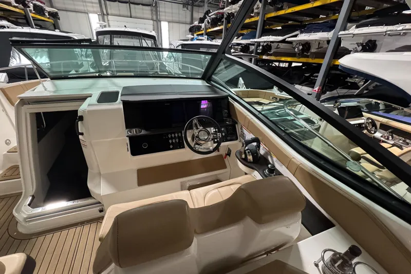  Yacht Photos Pics 2021 Sea Ray Sundancer 320 cockpit with modern controls and beige seating in a showroom.