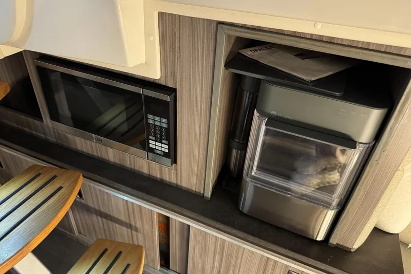  Yacht Photos Pics 2021 Sea Ray Sundancer 320 interior with microwave and ice maker in wooden cabinetry.