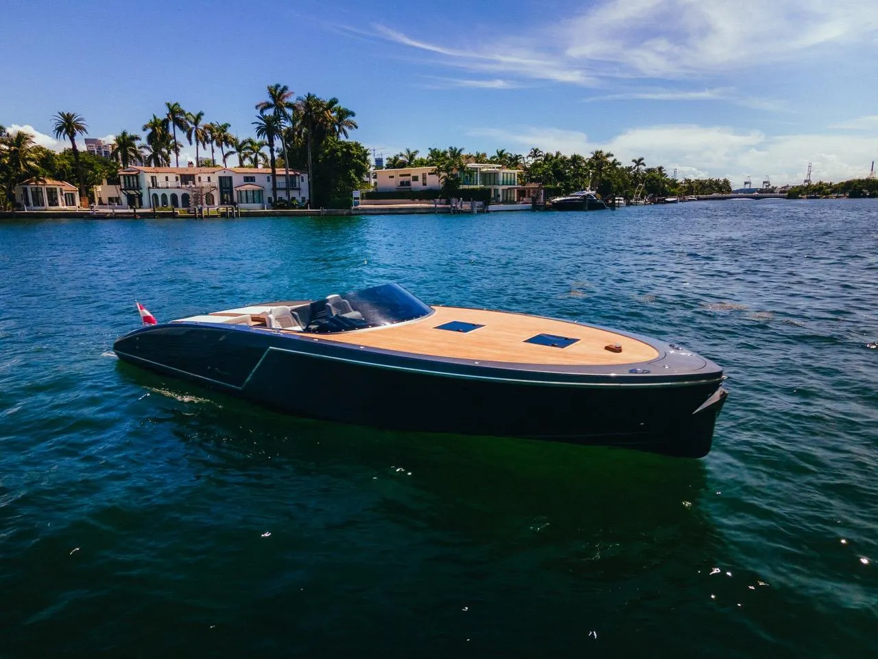 2020 Frauscher 1017 GT luxury yacht cruising on a sunny day near waterfront homes.