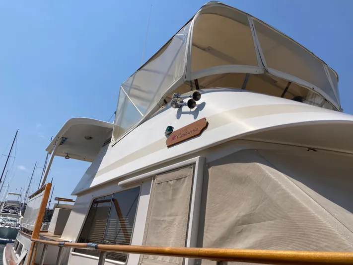  Yacht Photos Pics 1985 Offshore Yachts 48 Yachtfisher with canopy, docked under clear blue sky.