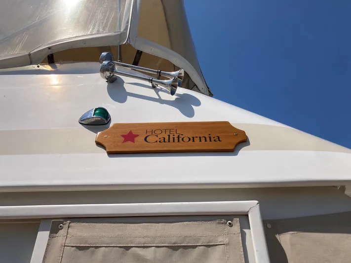  Yacht Photos Pics 1985 Offshore Yachts 48 Yachtfisher with "Hotel California" sign under clear blue sky.