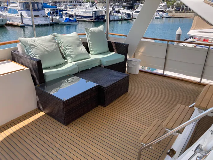  Yacht Photos Pics 1985 Offshore Yachts 48 Yachtfisher deck with wicker seating and glass table, docked at marina.