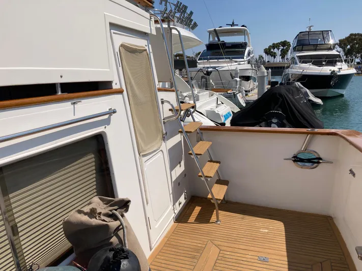  Yacht Photos Pics 1985 Offshore Yachts 48 Yachtfisher docked, featuring wooden deck and ladder, surrounded by other boats.
