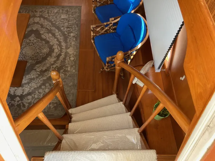  Yacht Photos Pics Interior of 1985 Offshore Yachts 48 Yachtfisher with wooden stairs and blue-cushioned chairs.