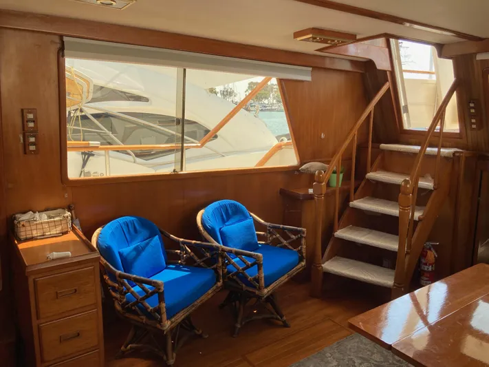  Yacht Photos Pics Interior of 1985 Offshore Yachts 48 Yachtfisher with blue-cushioned chairs and wooden stairs.