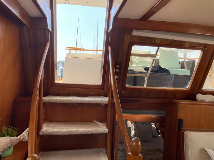  Yacht Photos Pics Interior view of 1985 Offshore Yachts 48 Yachtfisher, featuring wooden stairs and cozy seating.