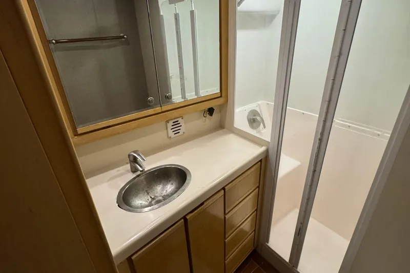  Yacht Photos Pics 1996 Bertam Convertible bathroom with sink, mirror, and shower enclosure.