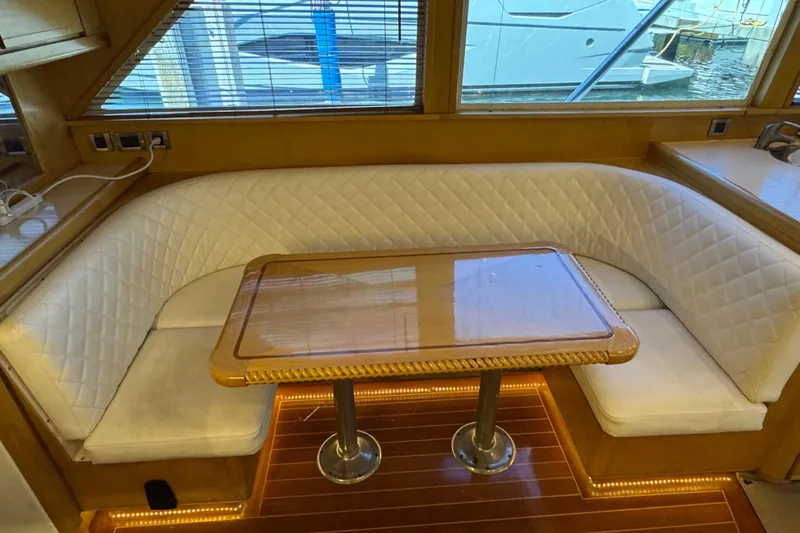  Yacht Photos Pics 1996 Bertam Convertible yacht interior with white cushioned seating and wooden table.