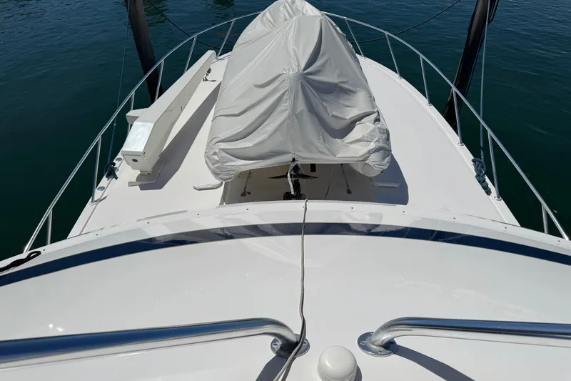  Yacht Photos Pics 1996 Bertam Convertible boat deck with covered equipment, docked on calm water.