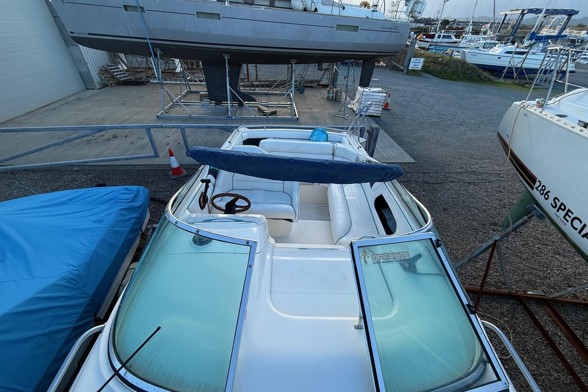 Fletcher Arrowbolt 25 boat, 2000 model, docked with open cockpit and blue cover.
