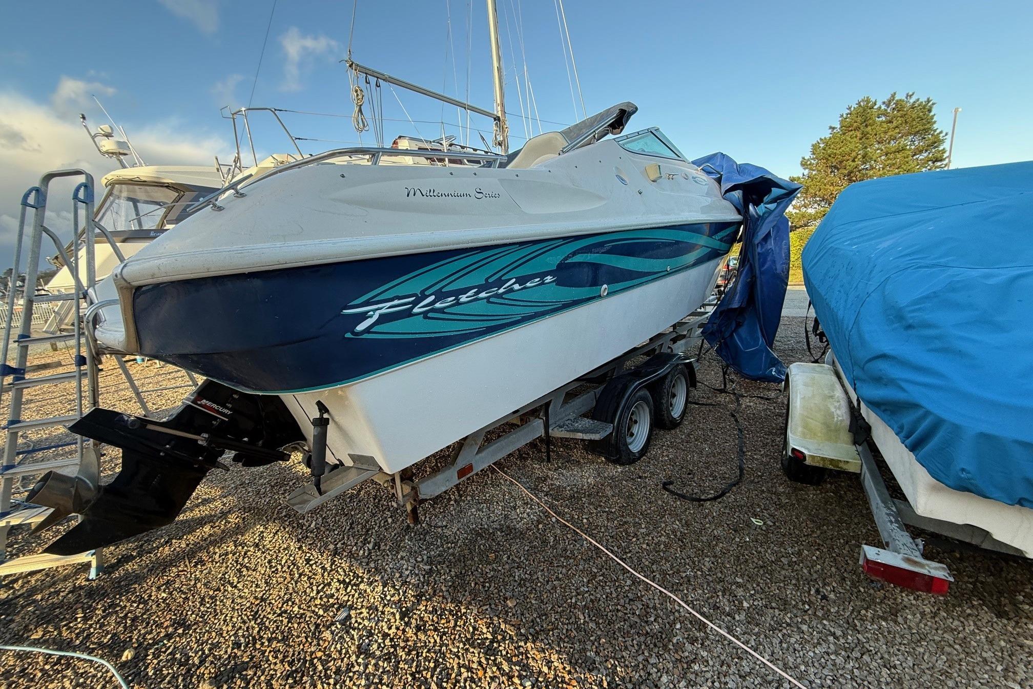 2000 Fletcher Arrowbolt 25 boat on trailer, parked outdoors under clear sky.