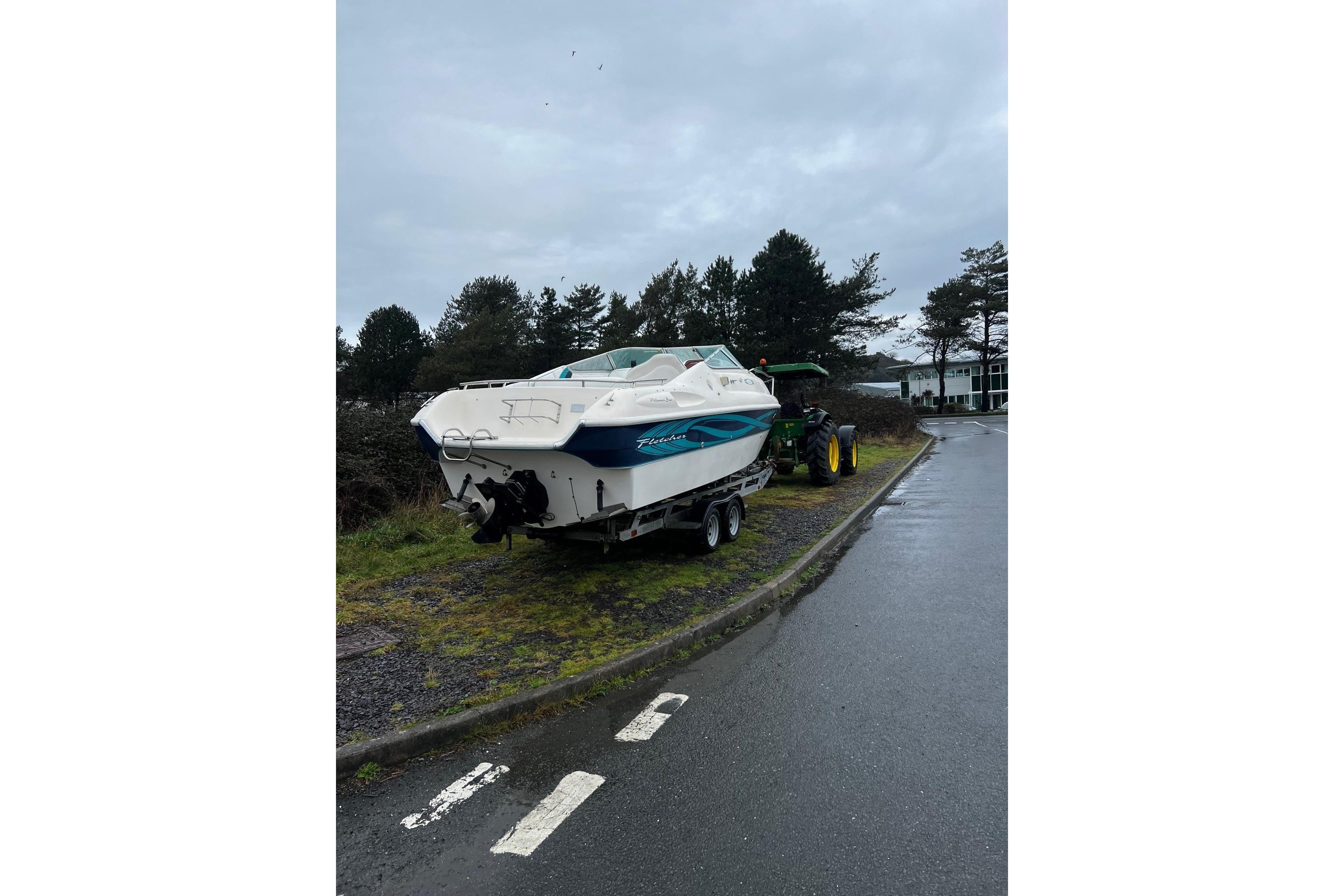 2000 Fletcher Arrowbolt 25 boat on trailer, parked roadside with overcast sky.